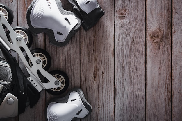 Inline skates with knee and elbow pads on wooden background
roller copy space selective focus