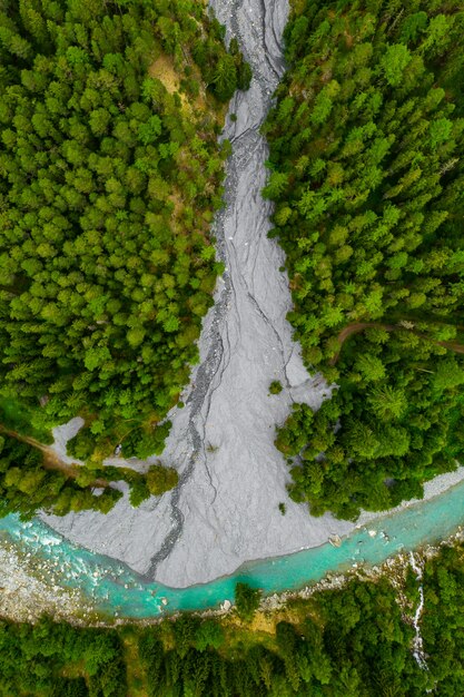 Inn River flowing in the forest in Switzerland. Aerial view from drone on a blue river in the mountains