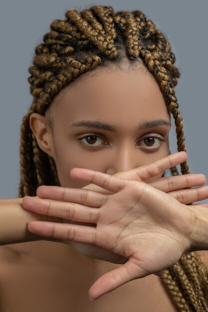 Inner pain. Sad young African American woman closing her mouth with crossed hands, showing her palms