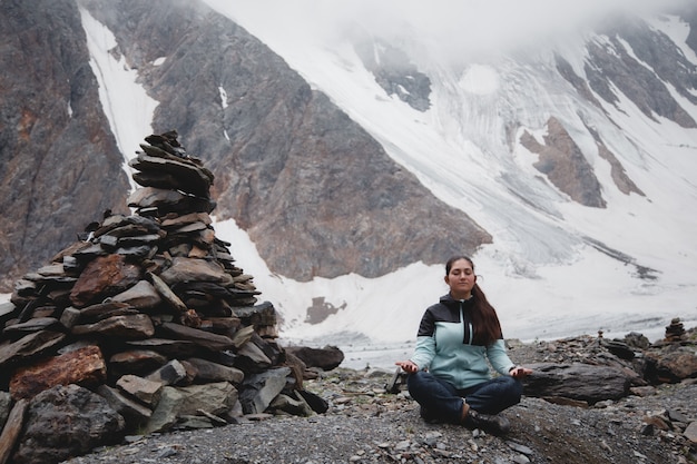 Внутренний мир и забота. Женщина медитирует с прекрасным видом на заснеженные горы. Актру ледник нагорье
