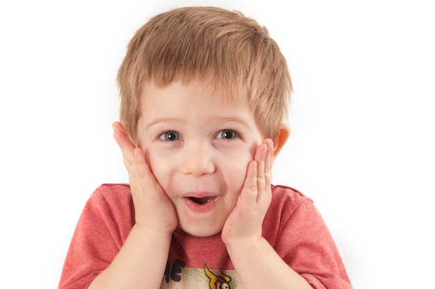 白い背景に立っている無邪気な少年が顔をしている