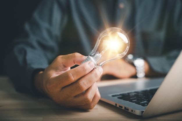 Innovation and inspiration Businessman holds a creative light bulb representing a new idea Depicts the concept of brainstorming solution and successful profit in global business