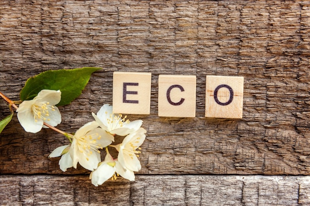 Inscriptie ECO letters woord en jasmijn bloem op oude rustieke houten achtergrond