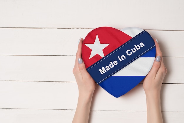 Inscriptie gemaakt in Cuba, de vlag van Cuba. Vrouwelijke handen met een hartvormige doos.