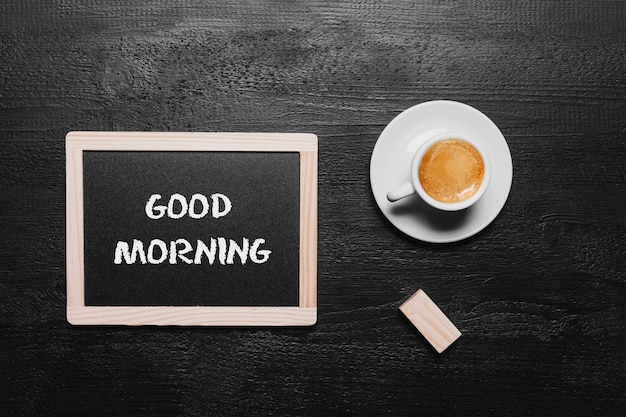 Inscriptie Goedemorgen in een kopje koffie en houten achtergrond