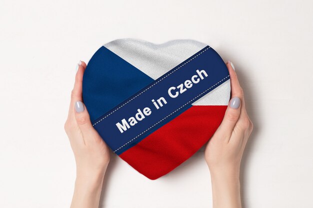 Inscriptie Made in Czech de vlag van Tsjechië. Vrouwelijke handen met een hartvormige doos. .