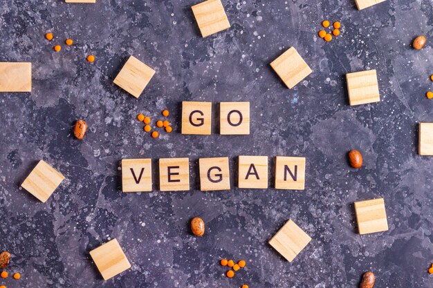 Inscriptie wordt vegan in houten letters met rauwe bonen en oranje linzen