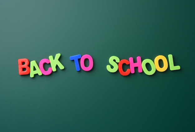 Inscription back to school from multicolored plastic letters on green chalk board