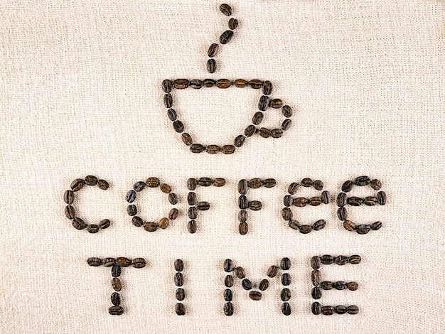 Время кофе надписи из жареных кофейных зерен на светло-коричневом холсте, вид сверху, выборочный фокус
