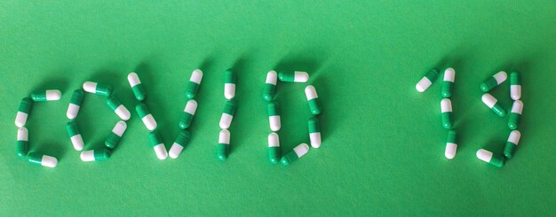 Надпись Covid 19 из букв из таблеток на зеленом фоне