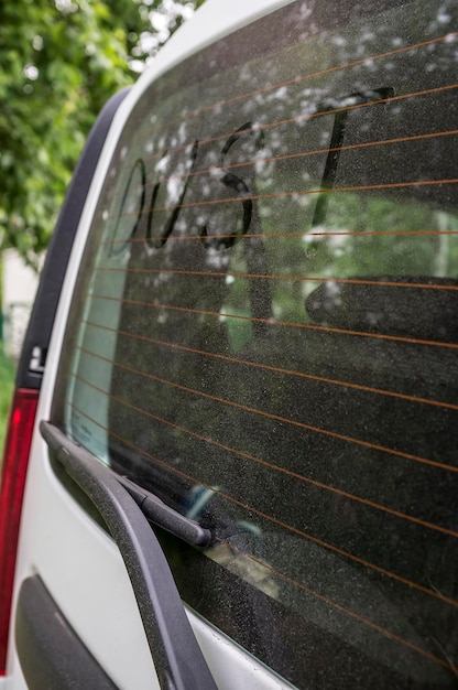 La scritta polvere sul lunotto sporco dell'auto