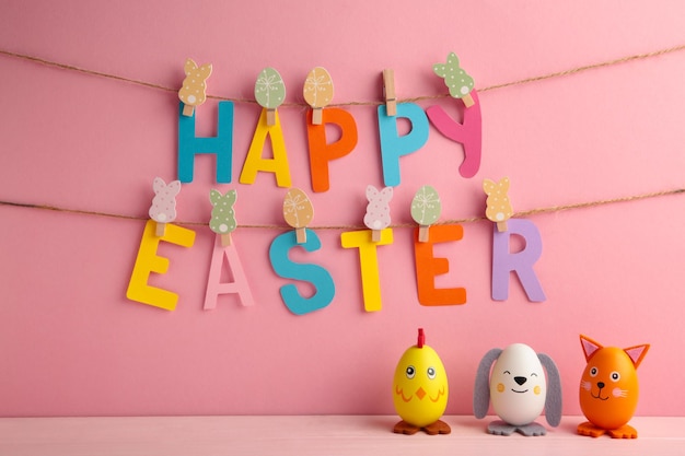 Photo inscription easter on rope with clothespins and eggs. the concept of postcards for the easter holiday on pink bsckground. top view