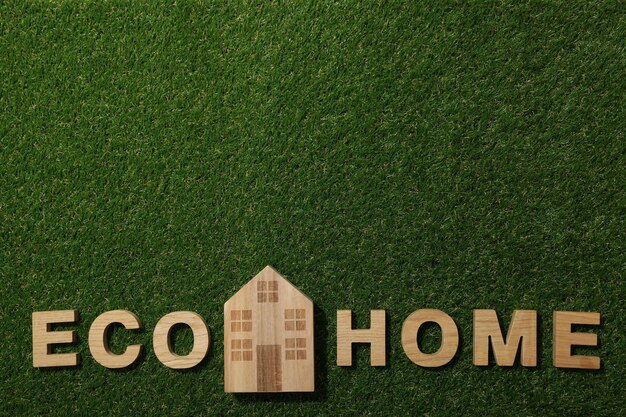 The inscription eco house in wooden letters on the grass