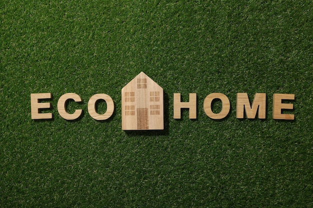 The inscription eco house in wooden letters on the grass
