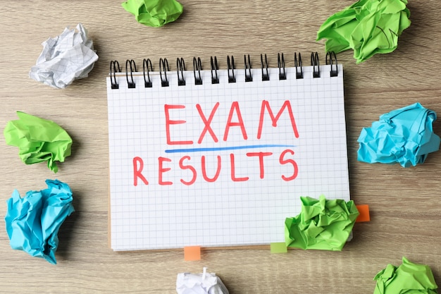 Photo inscription exam,results and paper balls on wooden table, top view