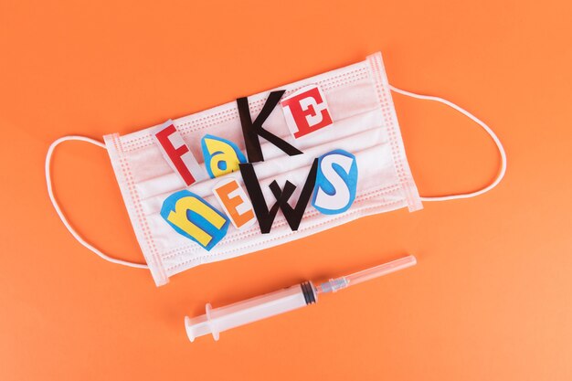 Photo inscription fake news with medical face mask and syringe