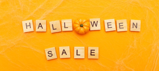 Photo the inscription halloween sale with little pumpkin on orange background with spider web banner