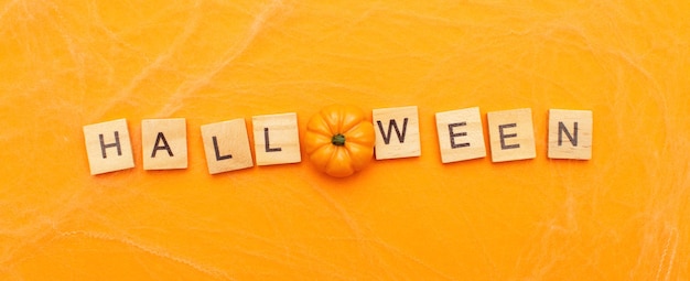 La scritta halloween sale con piccola zucca su sfondo arancione con banner ragnatela