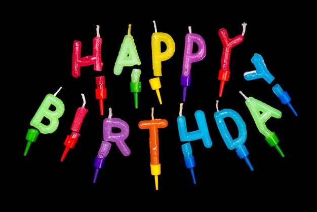 Photo inscription happy birthday made of multicolored festive candles on a black background isolated