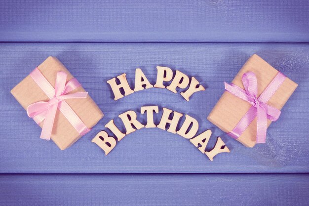 Photo inscription happy birthday and wrapped gifts with ribbon on boards