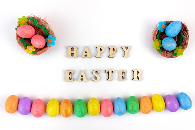 The inscription Happy Easter on a white background with colored eggs and bird nests