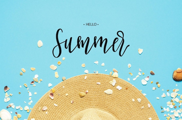 Photo inscription hello summer summer vacation concept flat lay hat and seashells on blue background image