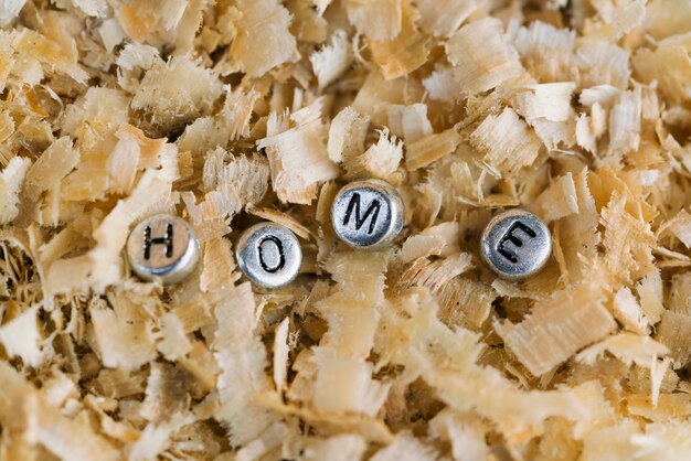 Inscription HOME made of silver metallic beads with letters on the background of sawdust