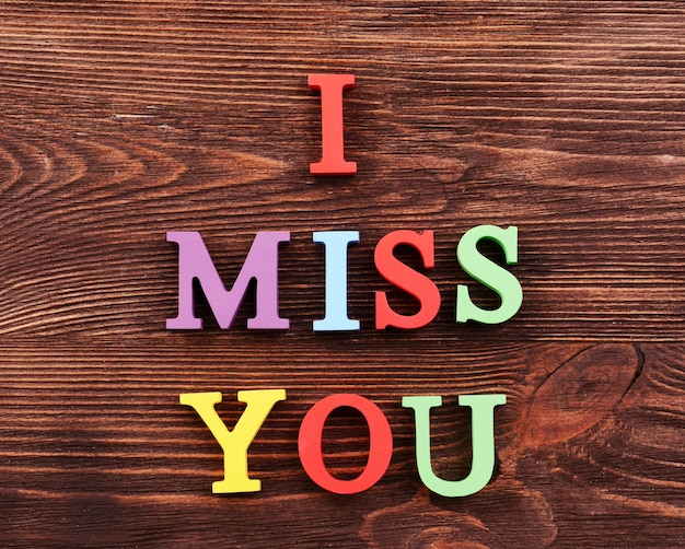 Photo inscription i miss you made of colorful letters on wooden background