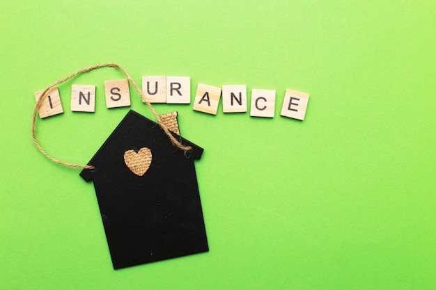 Photo inscription insurance with a little house on a green background made by wooden blocks