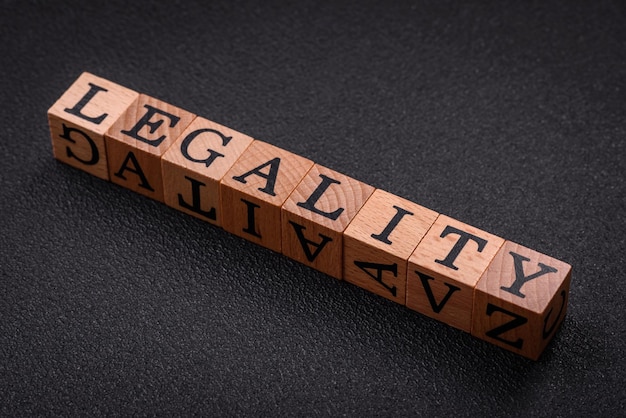 Photo the inscription legality on wooden cubes on a dark concrete background