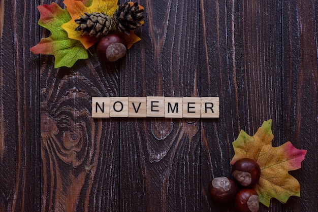 the inscription of the letters stands on a wooden background Autumn word on blurry colorful autumn