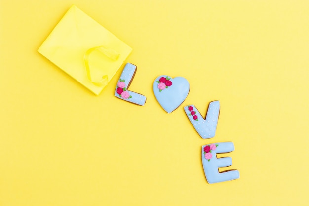 Inscription Love by homemade cookies with blue icing on yellow