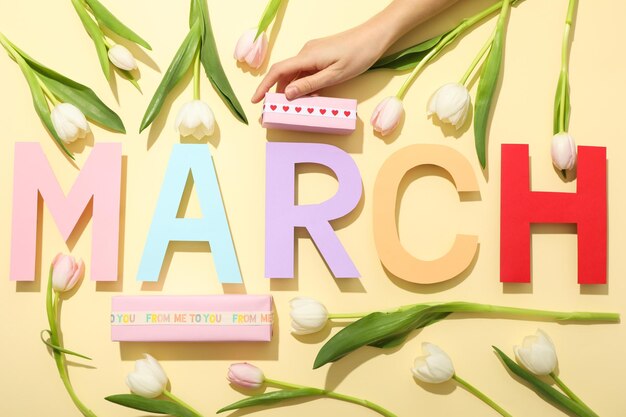 The inscription March in colorful letters with tulips