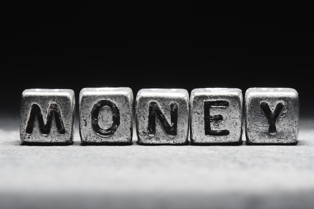 Inscription money on metal cubes in grunge style on a black background isolated