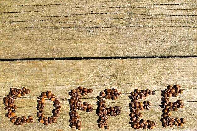 コピースペースと木の背景にコーヒー豆からコーヒーの碑文。上面図
