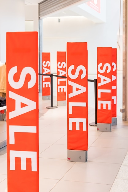 Inscription Sale on the background of a red glass wall in the store