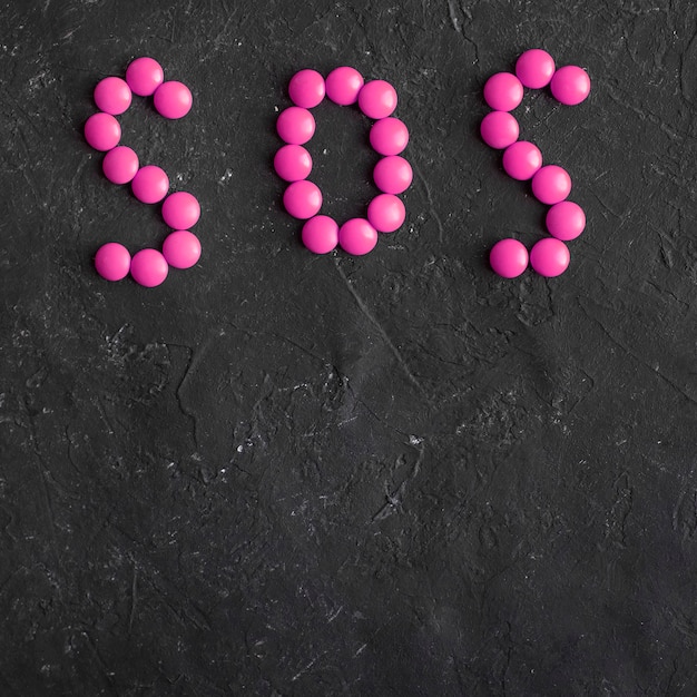 Inscription SOS made of round pills