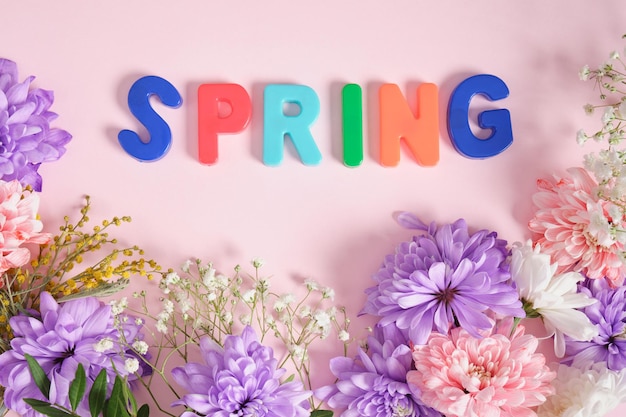 Inscription spring in flowers on a pink background top view spring mood concept