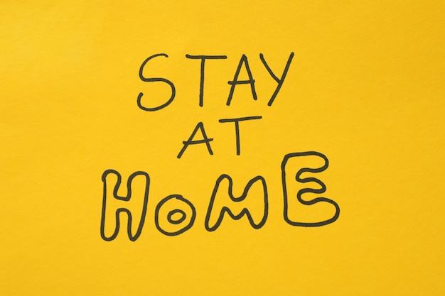 Inscription Stay at home on yellow surface. Quarantine