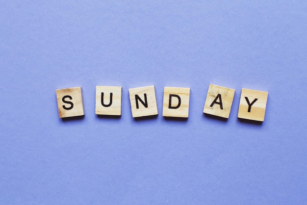 inscription sunday made by wooden cubes on a veri peri purple background