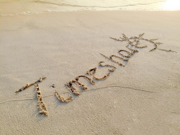 몰디브 열대 섬의 모래에 "Timeshare"라는 글자가 새겨져 있습니다.