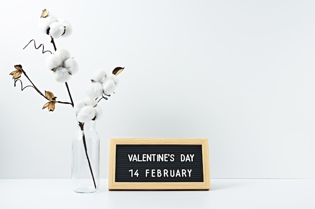 The inscription valentine's day in a frame of dry flowers in a transparent vase on white.