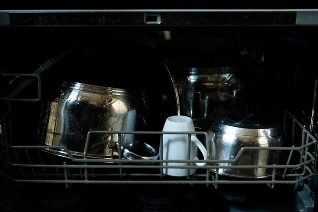 Inside the dishwasher the pans with cups are dirty