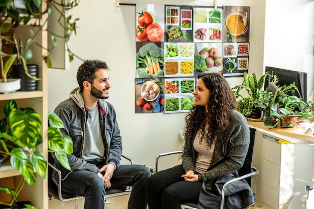 Inside a nutritionists consultation room a couple discusses their meal plan board showcases vibrant