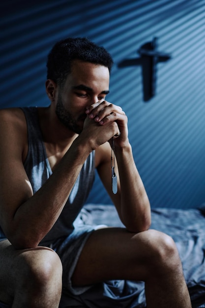 Insomniac guy with metallic medallions in hands praying in the middle of night