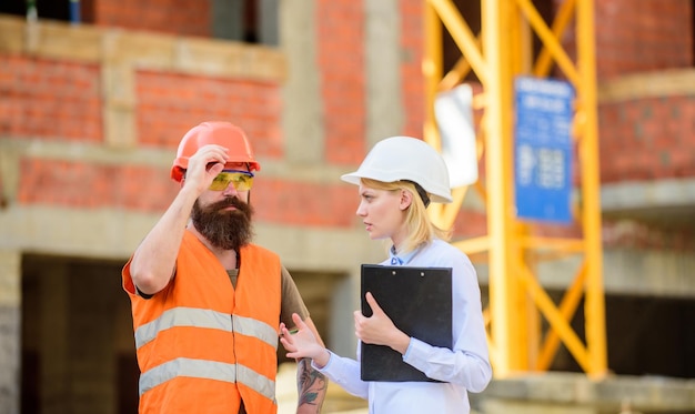 Inspecteur en bebaarde brutale bouwer bespreken bouwvoortgang Bouwproject inspecteren Correcties en boetes bouwinspectie bespreken voortgangsproject Veiligheidsinspecteurconcept