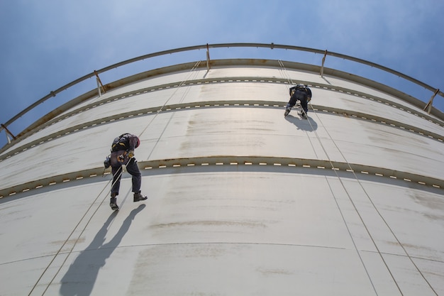 Inspectiefoto van twee arbeiders met touwtoegang vanaf de onderkant van de brandstoftanks.