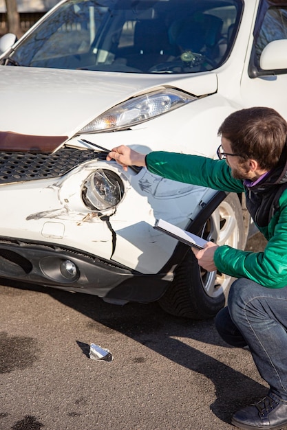 Inspection car after an accident road damage scratches on the bumper Broken car parts or closeup