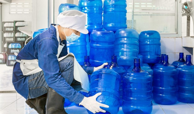 Inspection quality control man working in drink water factory checking water gallons before shipment