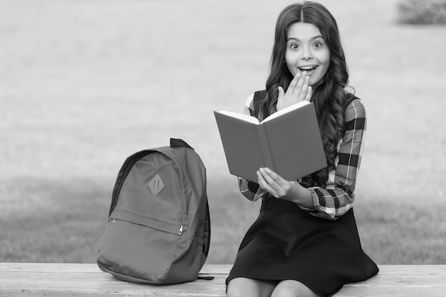 Inspiratie opdoen bij lezen Verrast kind leest boek zittend op een bankje Inspiratieconcept Schoolbibliotheek Alfabetiseringsonderwijs Net geïnspireerd